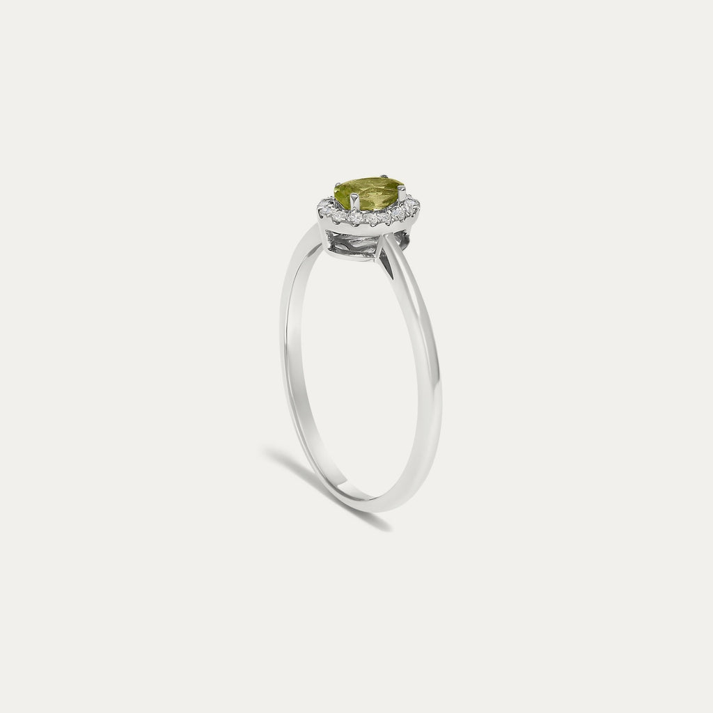 Profile view of the Origine birthstone halo ring in 10K white gold showing the raised halo setting with an oval peridot above the slim band