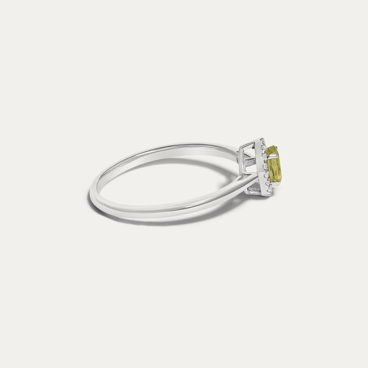 Side view of the Origine birthstone halo ring in 10K white gold with an oval peridot and a halo of natural diamonds above the slim band