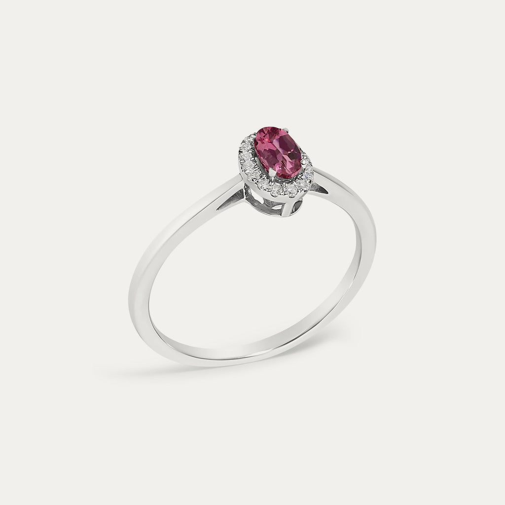 Angled view of the Origine birthstone halo ring in 10K white gold with an oval pink tourmaline and its halo of natural diamonds