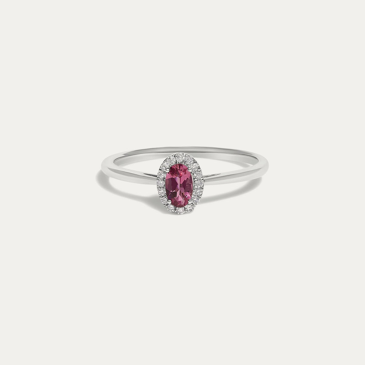 Front view of the Origine birthstone halo ring in 10K white gold with an oval pink tourmaline crowned by a halo of natural diamonds