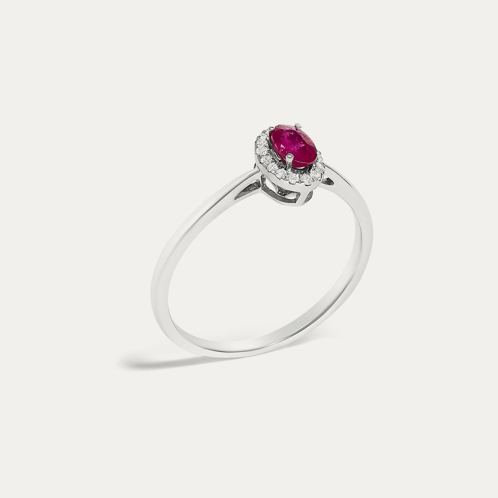 Angled view of the Origine birthstone halo ring in 10K white gold with an oval ruby and its halo of natural diamonds