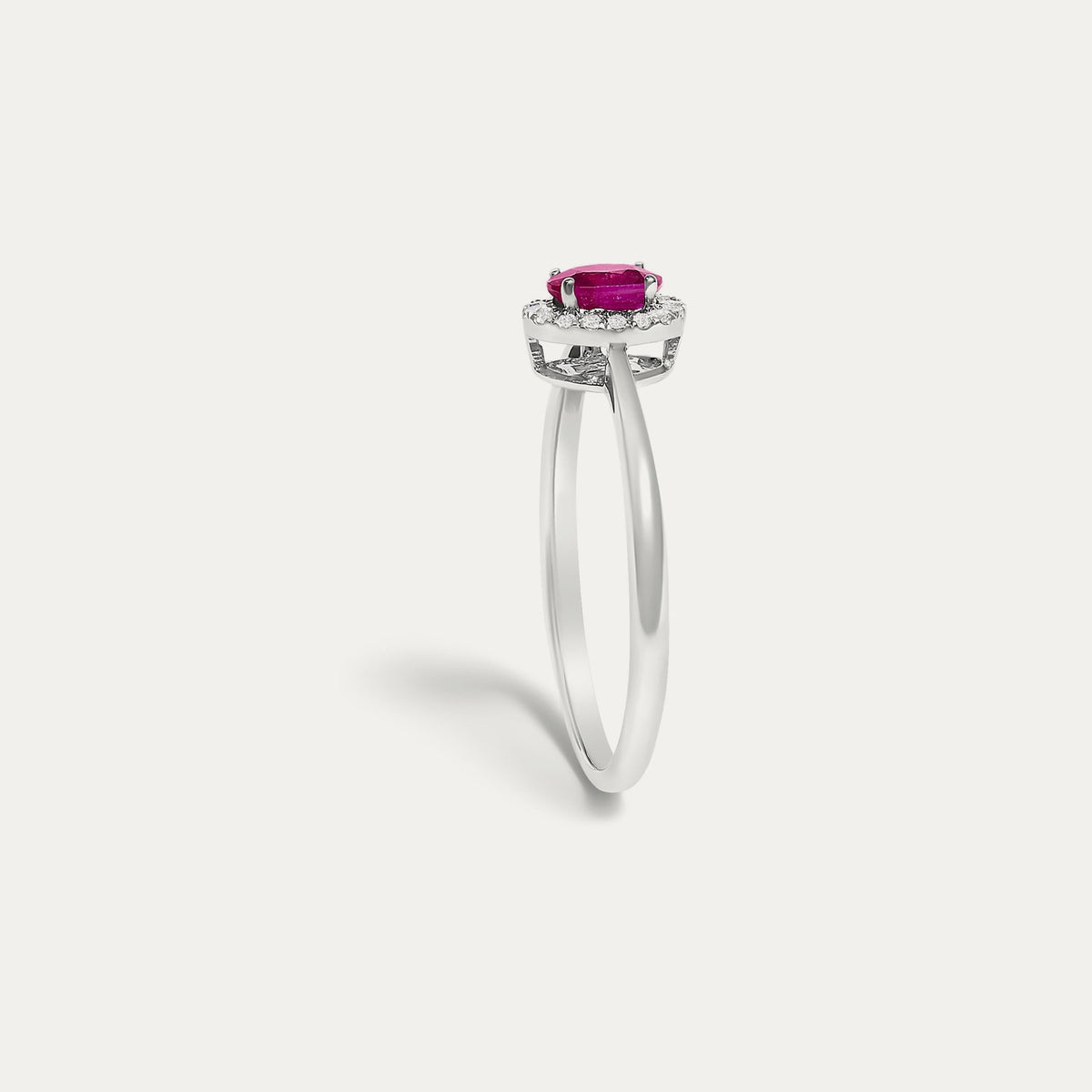 Profile view of the Origine birthstone halo ring in 10K white gold showing the raised halo setting with an oval ruby above the slim band