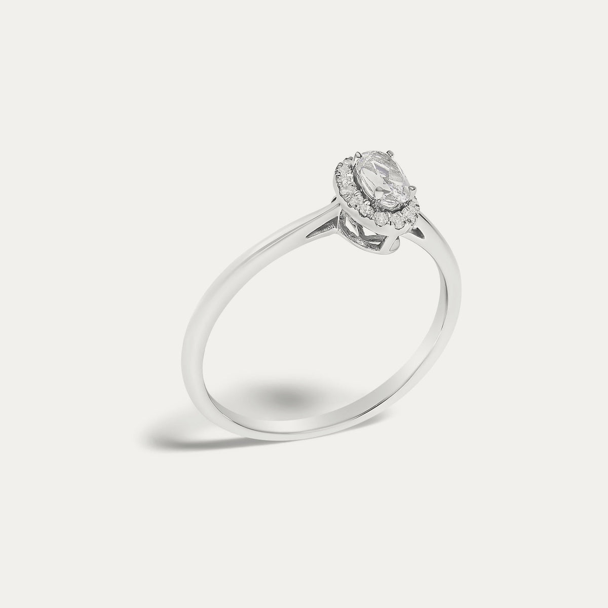 Angled view of the Origine birthstone halo ring in 10K white gold with an oval white topaz and its halo of natural diamonds