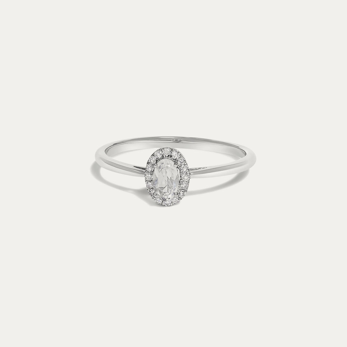 Front view of the Origine birthstone halo ring in 10K white gold with an oval white topaz crowned by a halo of natural diamonds