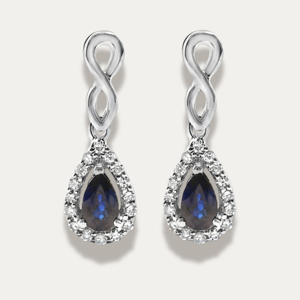 Pair of white gold earrings with sapphire gemstones on a grey background