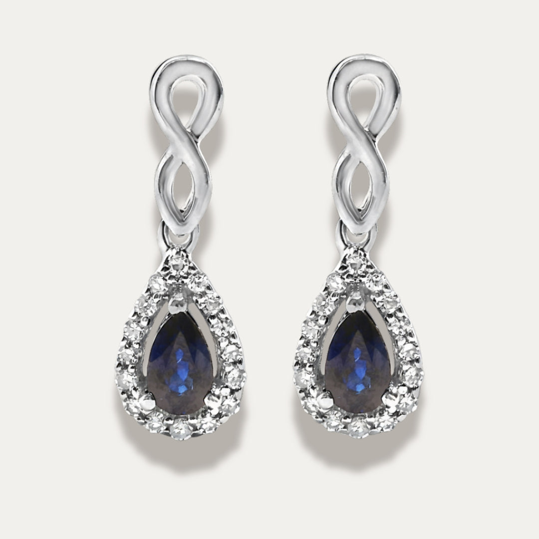 Pair of white gold earrings with sapphire gemstones on a grey background