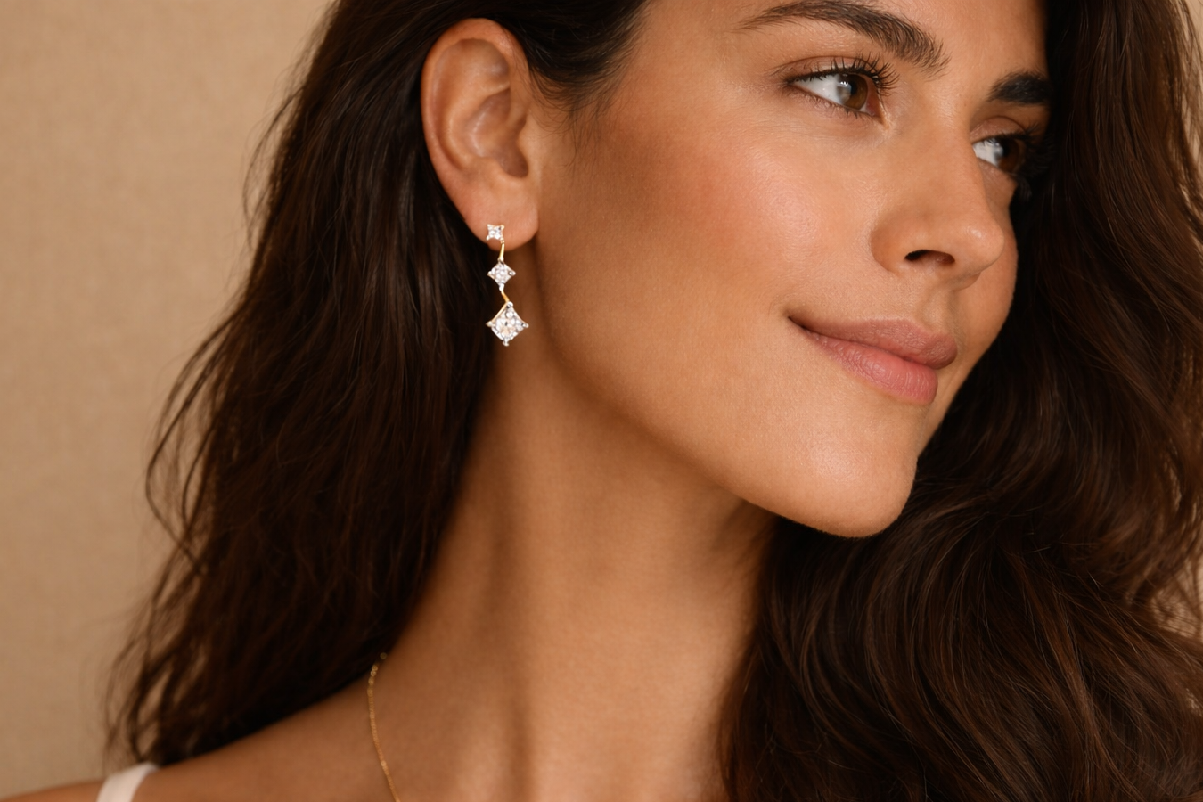 Close-up of a woman wearing a diamond earring with a beige background