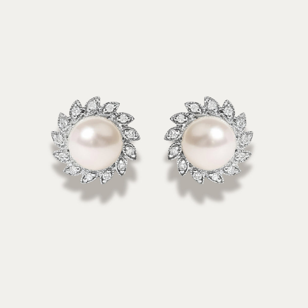 Pair of pearl earrings with diamonds on a light gray background