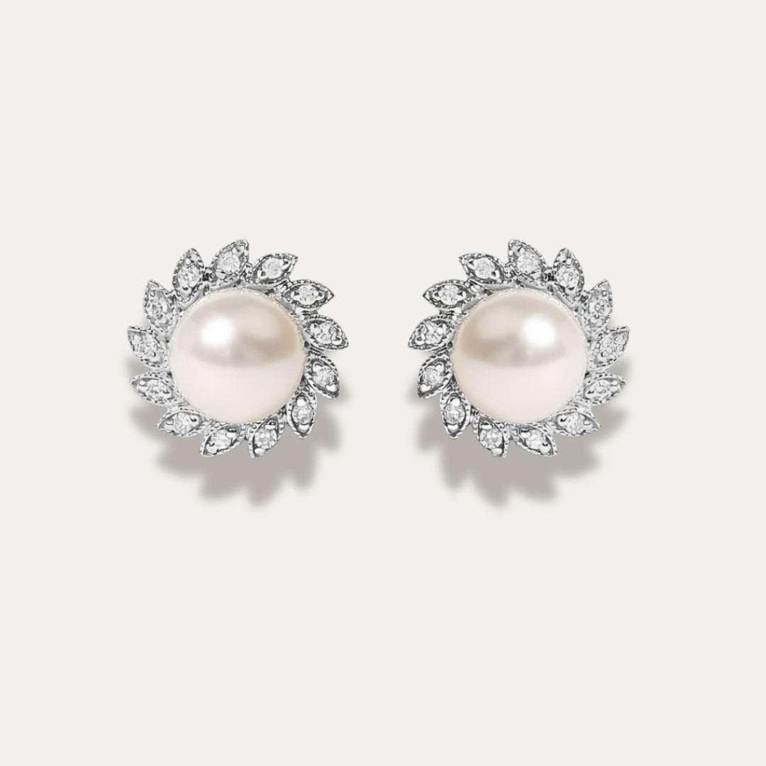 Pair of pearl earrings with diamonds on a light gray background