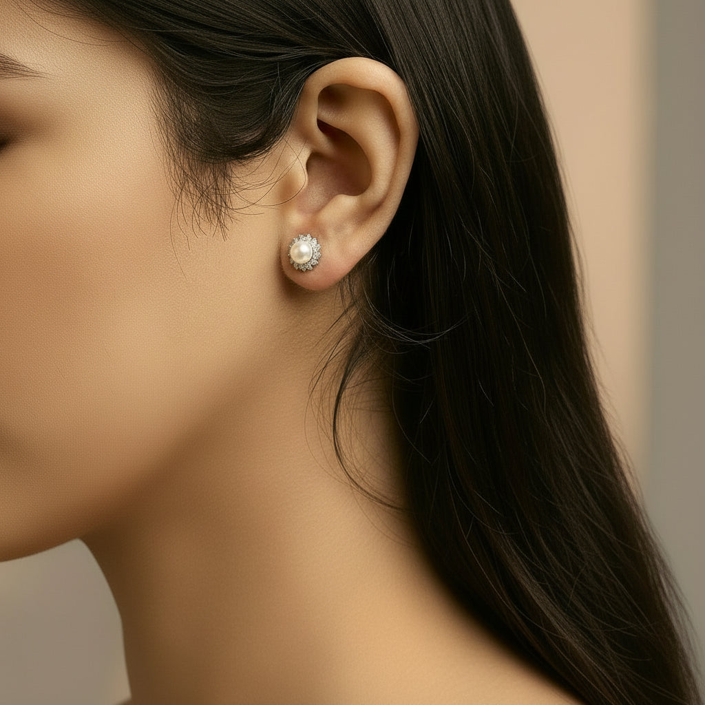 Alba Halo Stud Earrings worn on a model's earlobe, featuring luminous South Sea pearls encircled by sparkling diamonds in 10K white gold, capturing elegance and timeless sophistication.