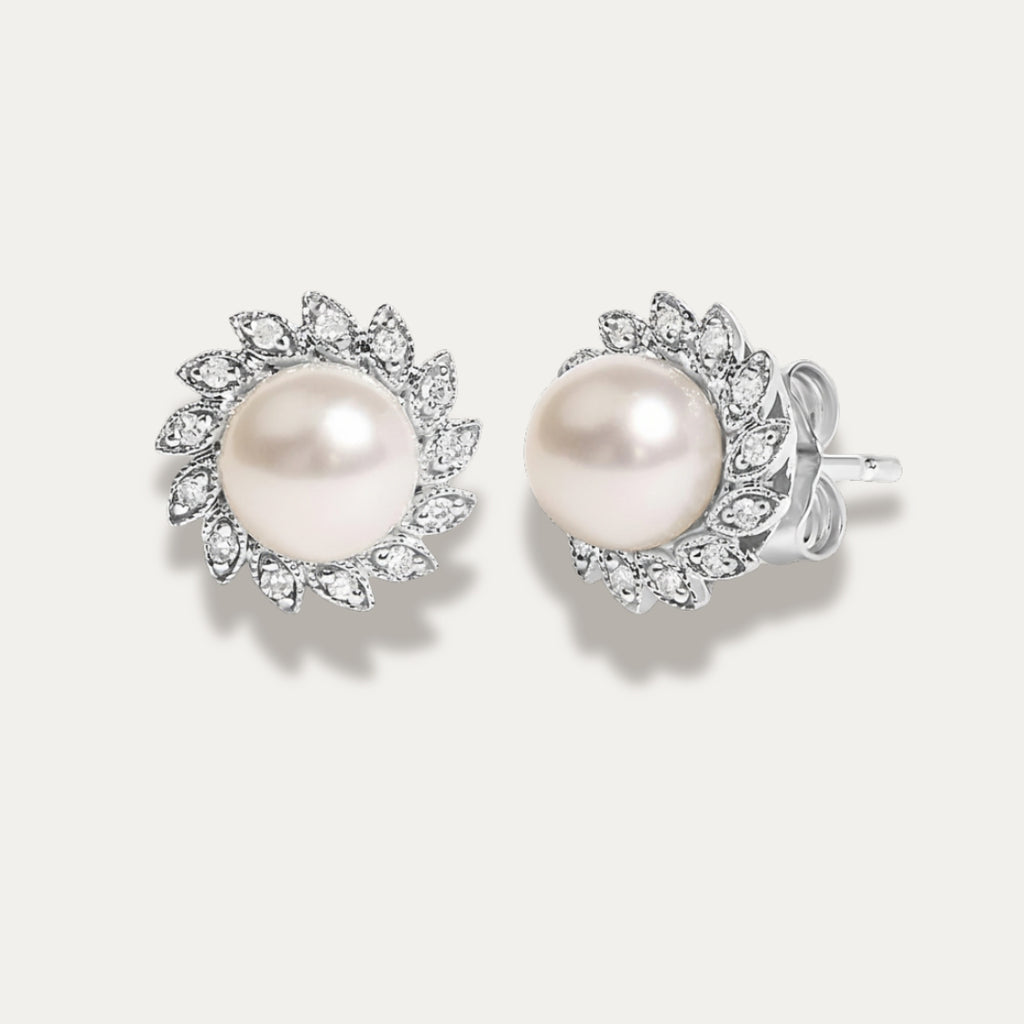 Pair of pearl earrings with diamonds on a light gray background