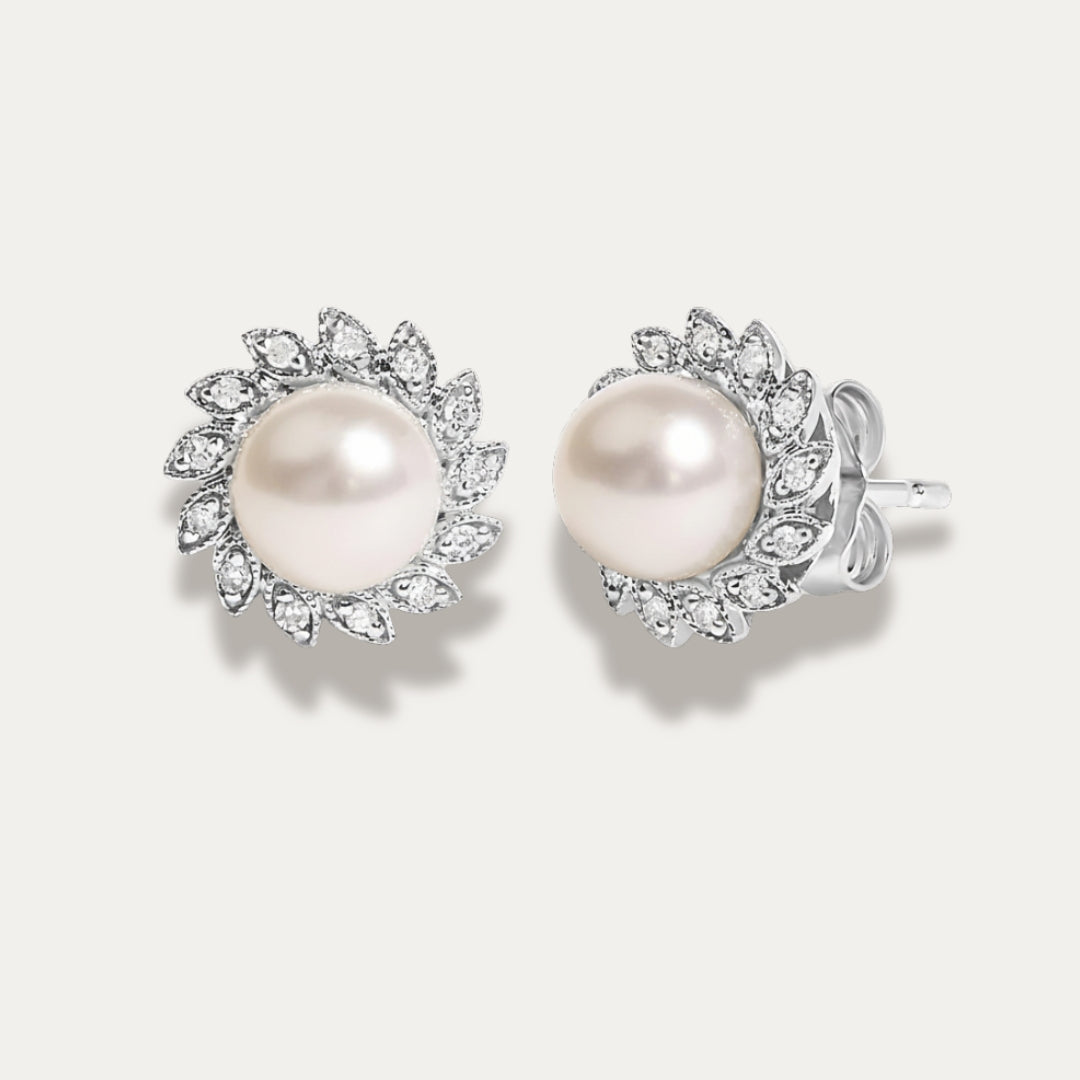 Pair of pearl earrings with diamonds on a light gray background
