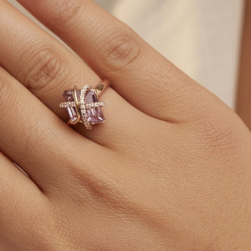 Close-up of a hand wearing a purple amethyst gemstone ring with a rose gold band.
