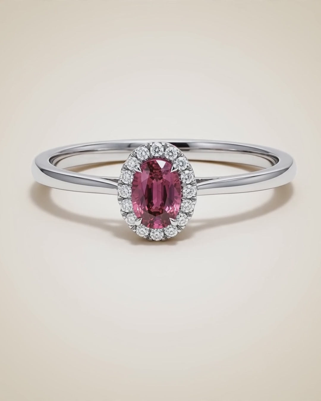 Video of the Origine birthstone halo ring in pink tourmaline rotating on a cream background