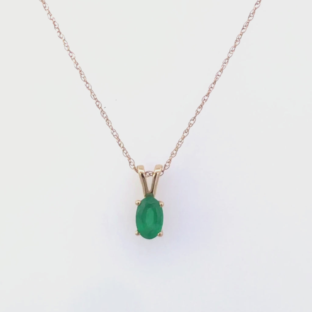 Video of gold necklace with a emerald green gemstone pendant on a white background