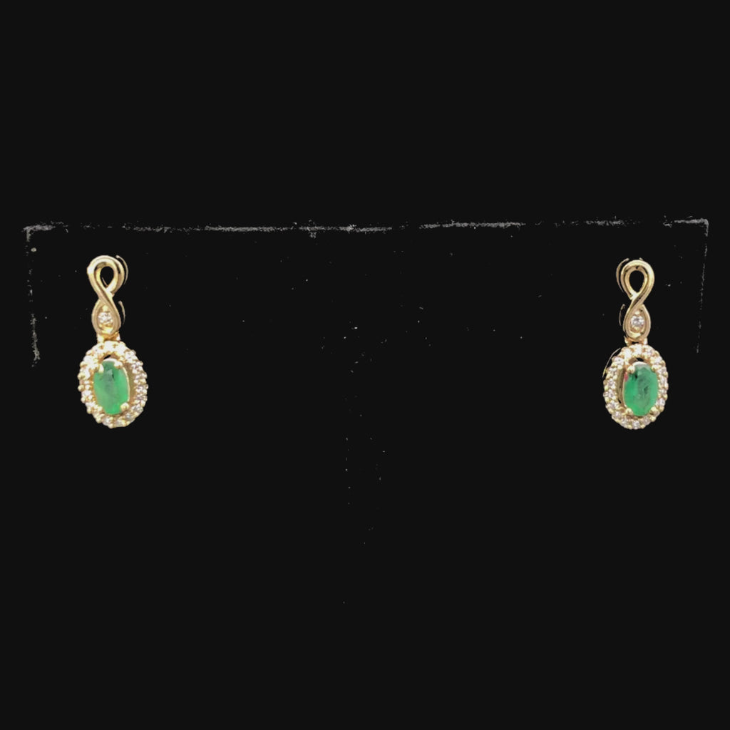 Video of Gold earrings with green gemstones on a black background