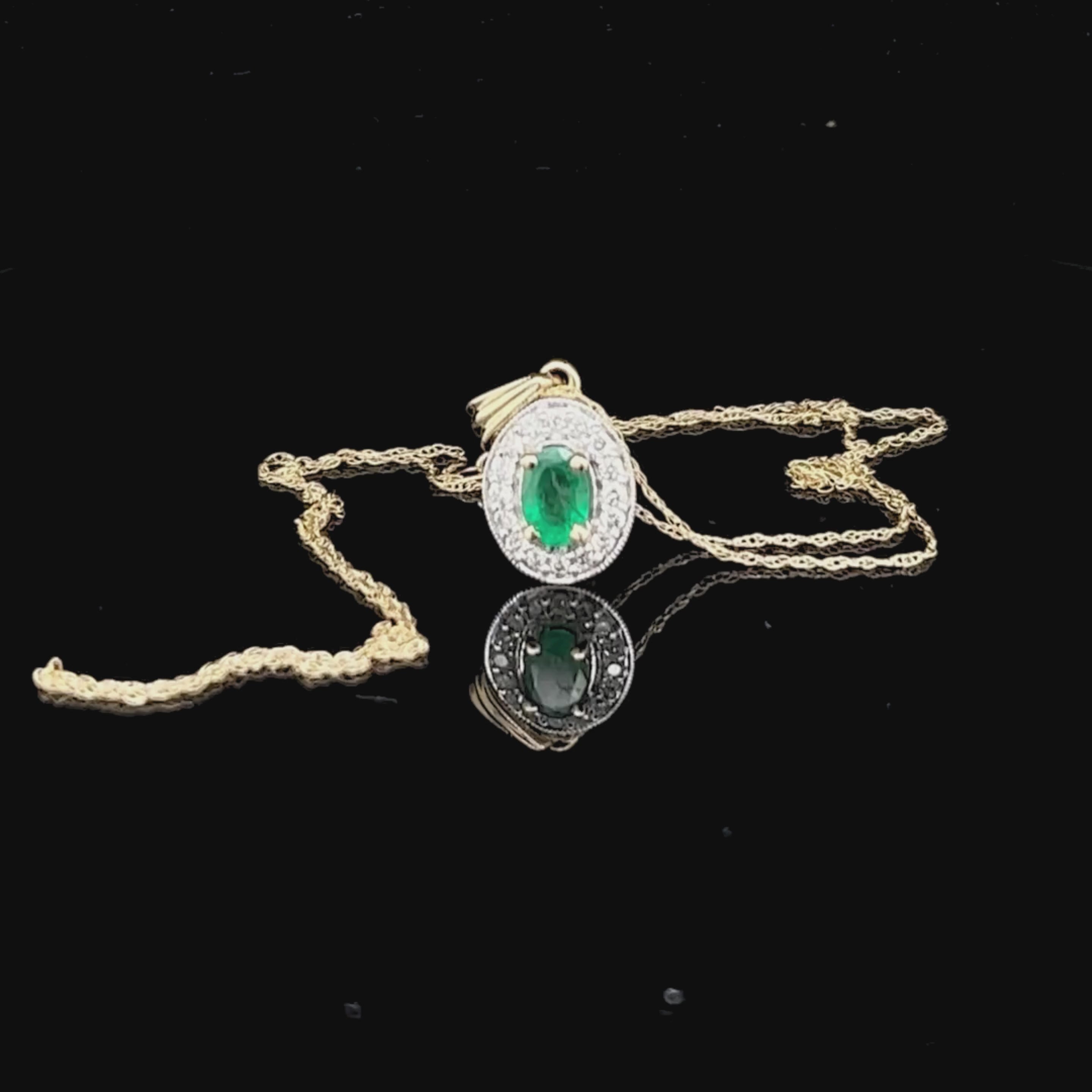 Video of gold pendant with a green emerald gemstone and diamond accents on a black background
