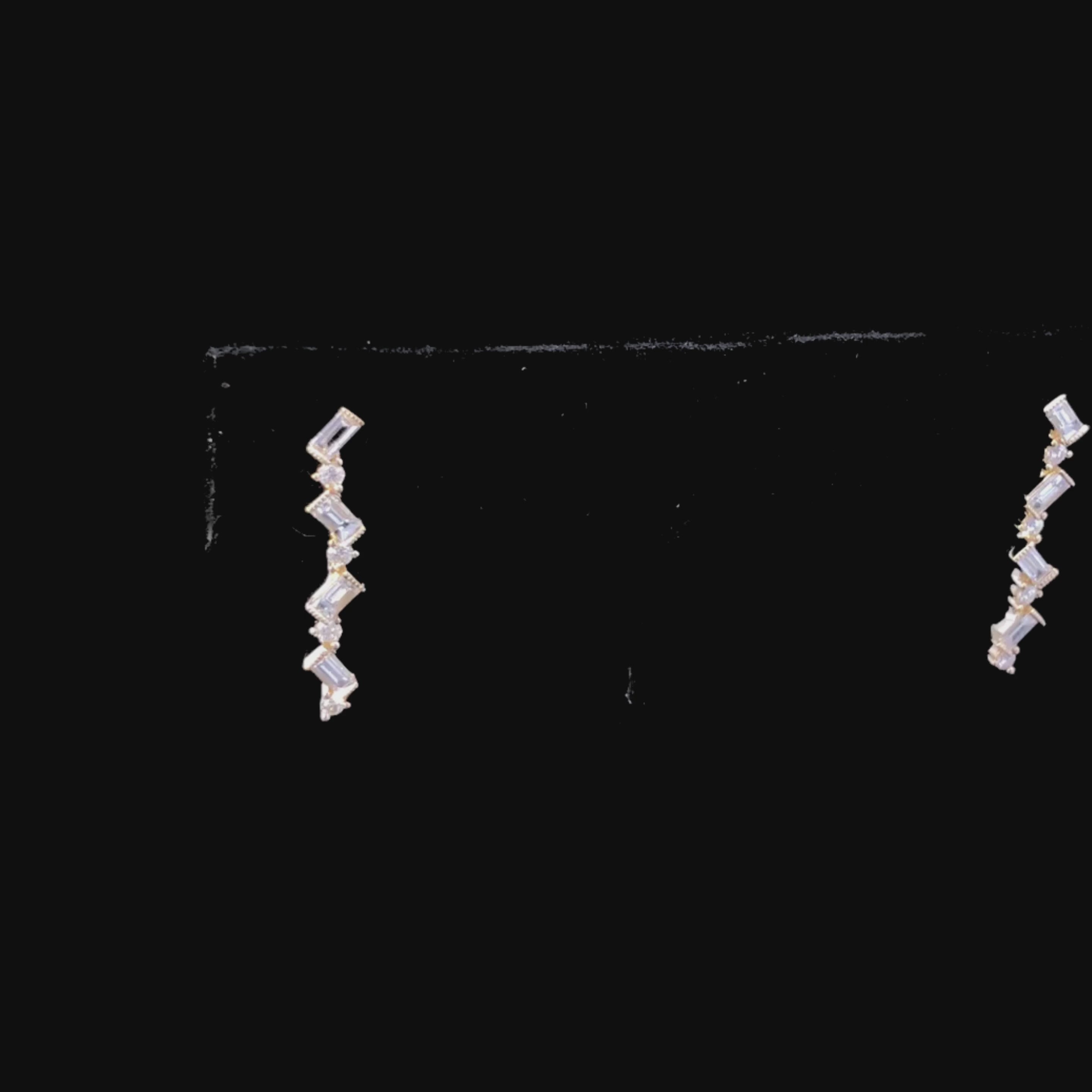 Video of gold zigzag earrings with diamonds on a black background