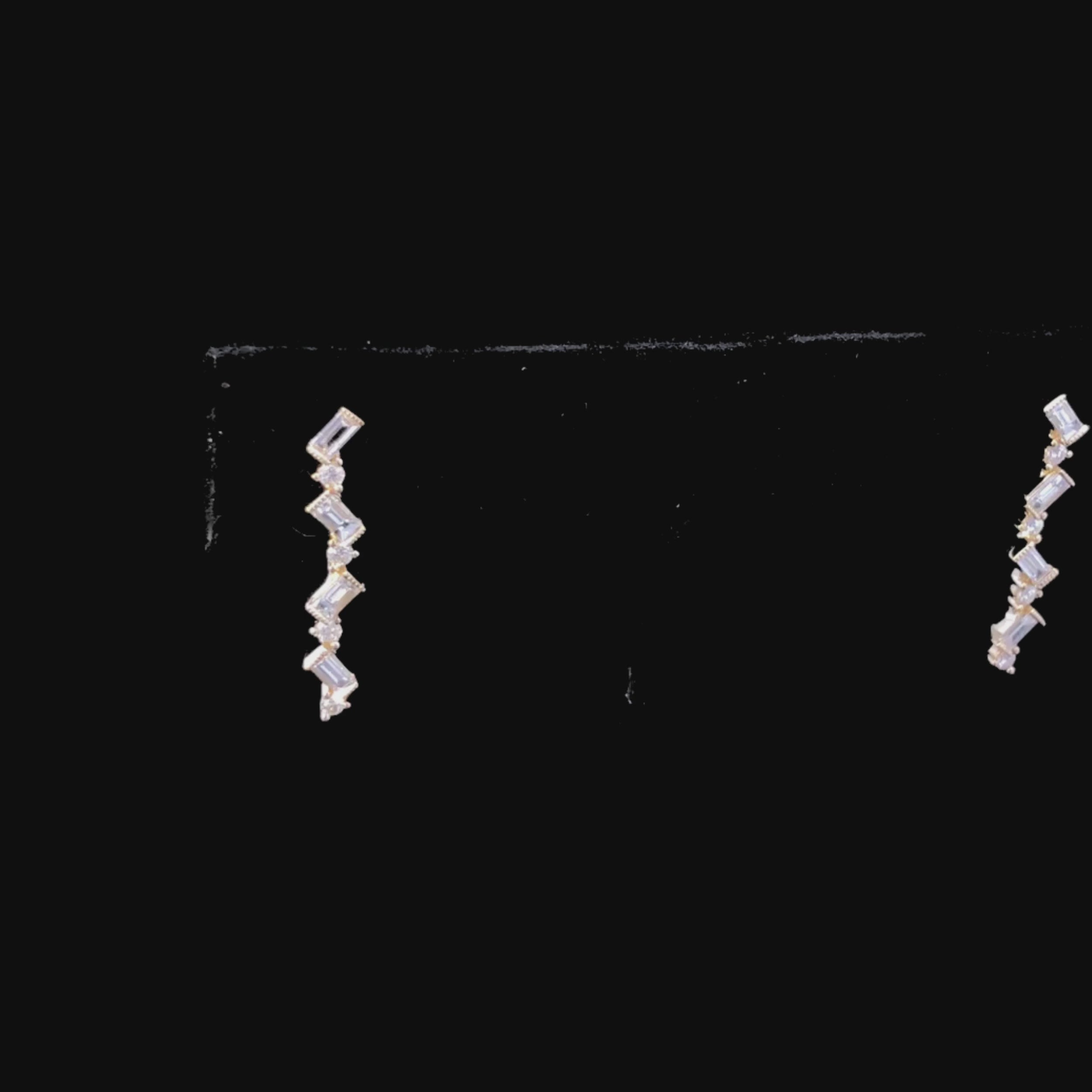 Video of gold zigzag earrings with diamonds on a black background
