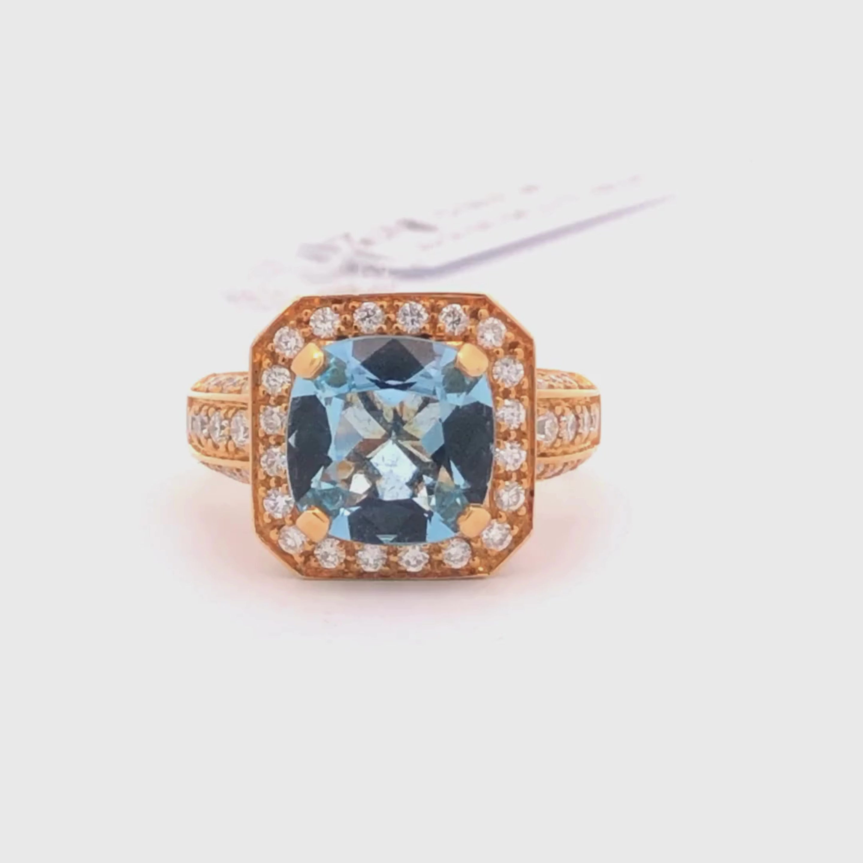 Video of 18K Rose gold ring with a blue aquamarine gemstone and diamond accents on a light gray background