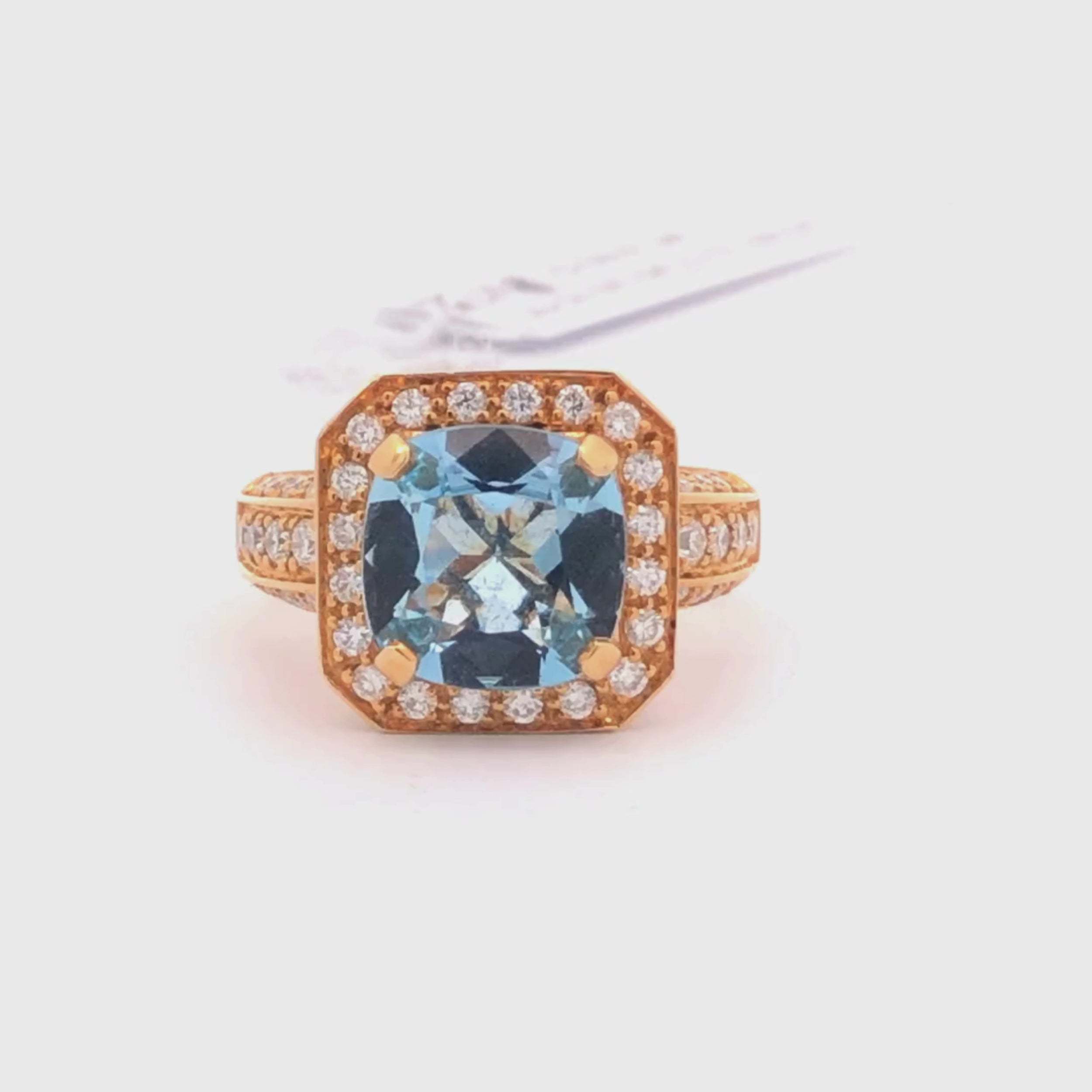 Video of 18K Rose gold ring with a blue aquamarine gemstone and diamond accents on a light gray background