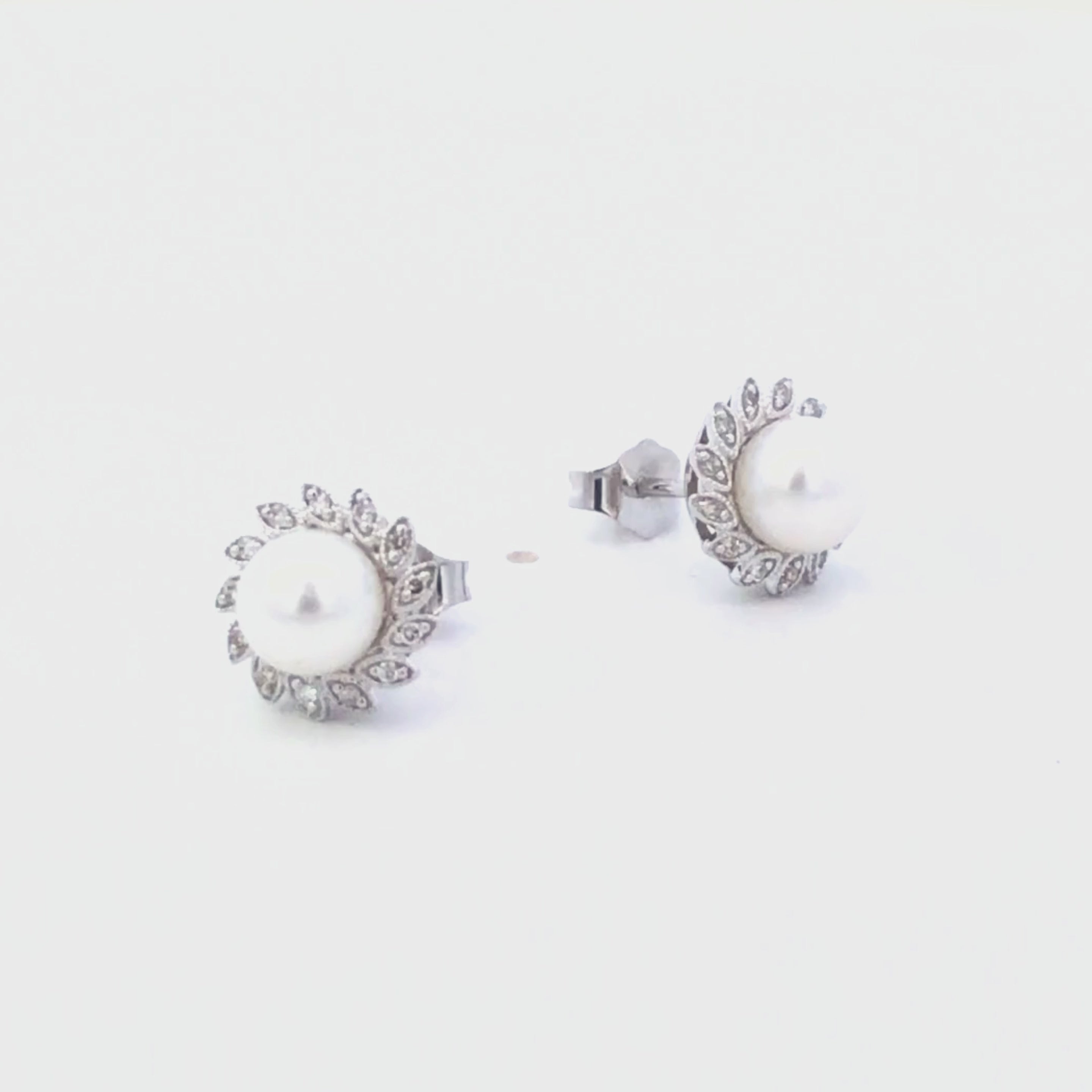 Video of pearl earrings with diamond accents on a white background