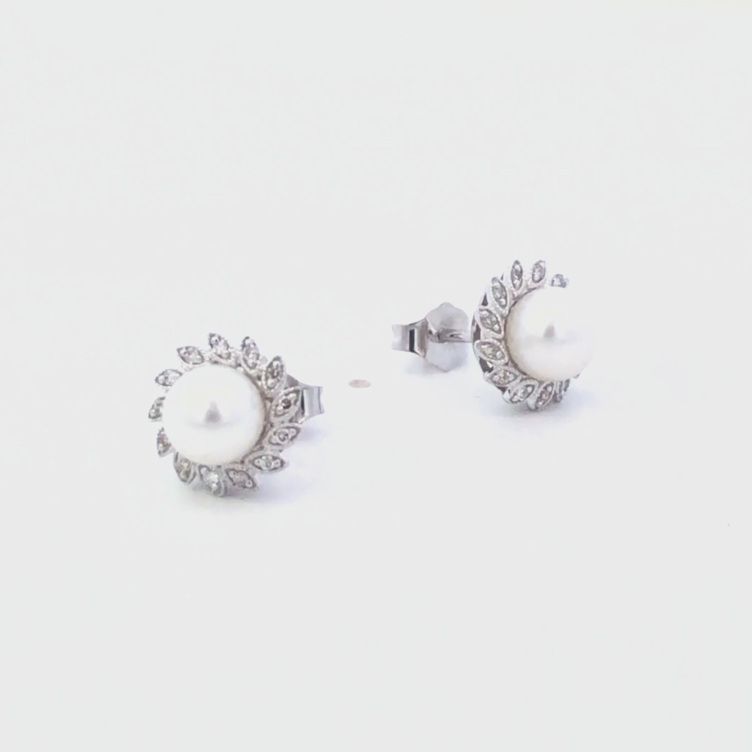 Video of pearl earrings with diamond accents on a white background