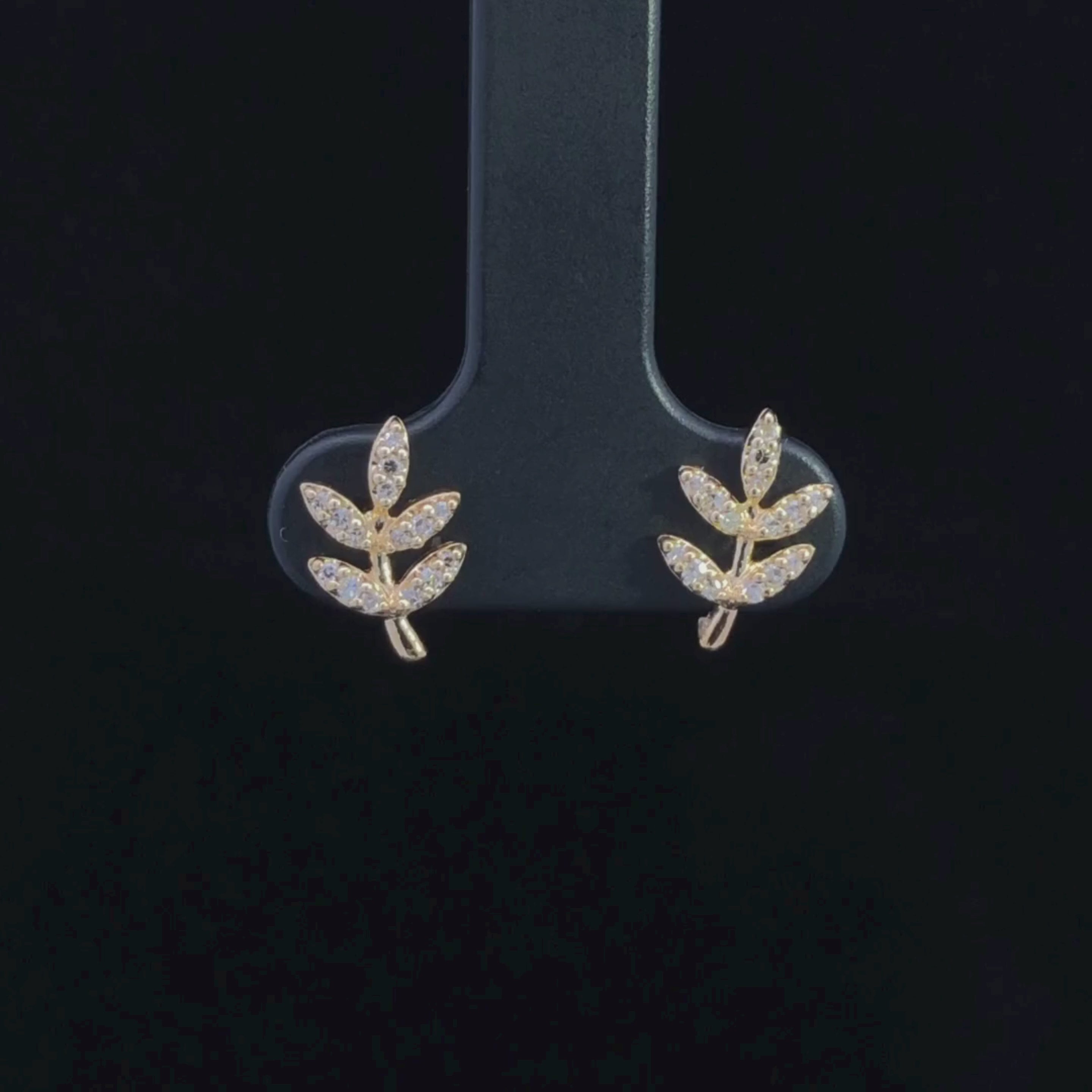Video of gold leaf-shaped earrings with diamond-like stones on a black background